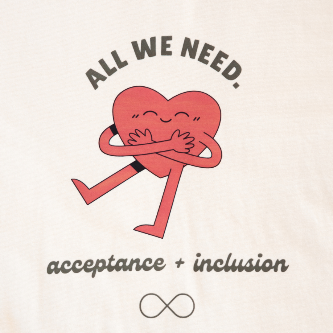 Close-up of All We Need t-shirt design on soft ivory Comfort Colors fabric, handmade neurodiversity advocacy apparel